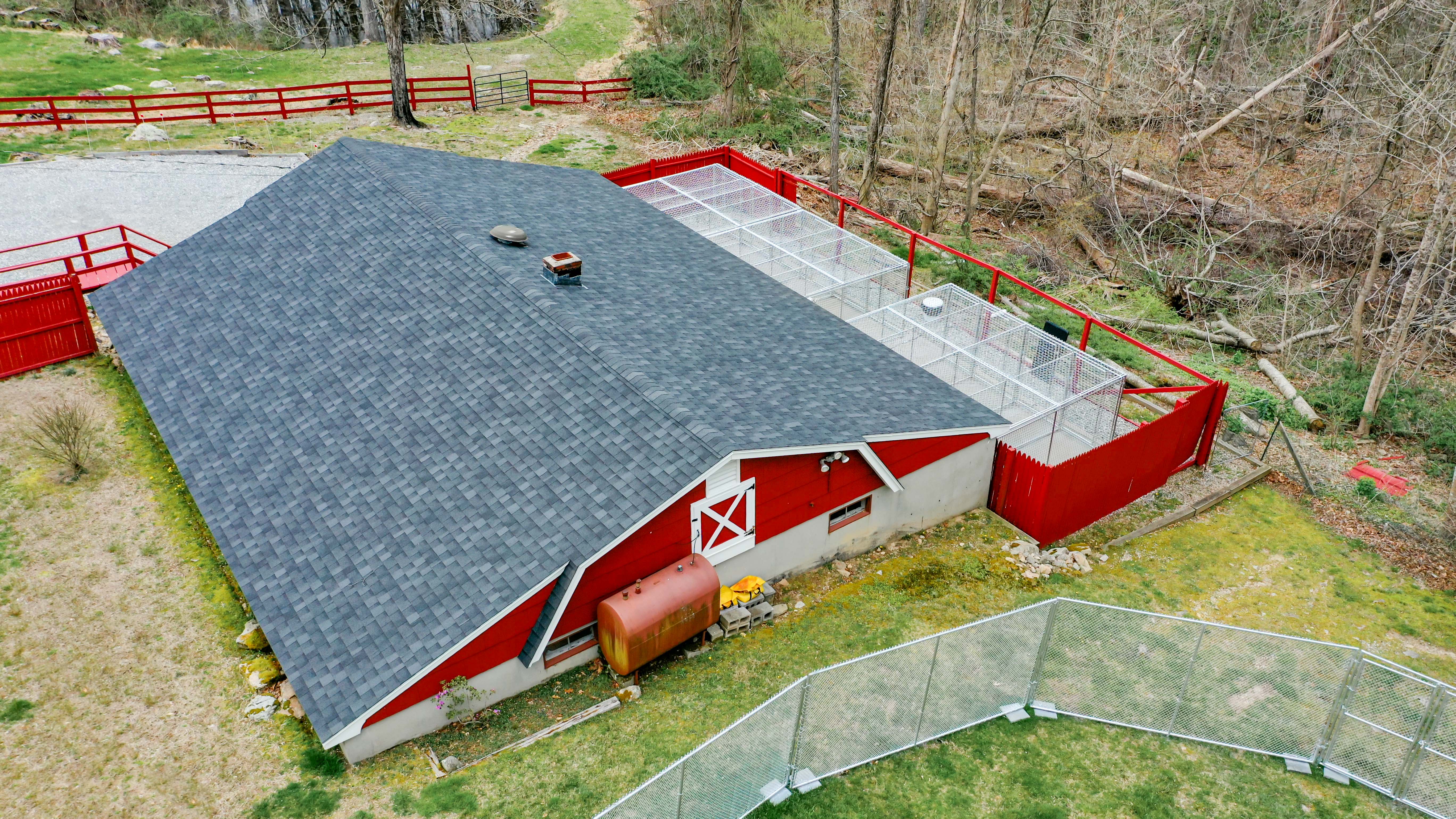 aerial shot of red commercial dog boarding business with outdoor kennels and kennel fencing for play areas