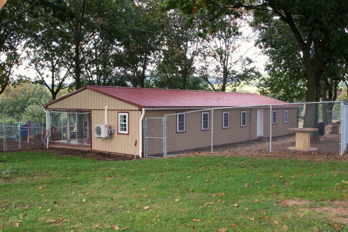 tan and red roofed commercial dog boarding business with outdoor fenced in area