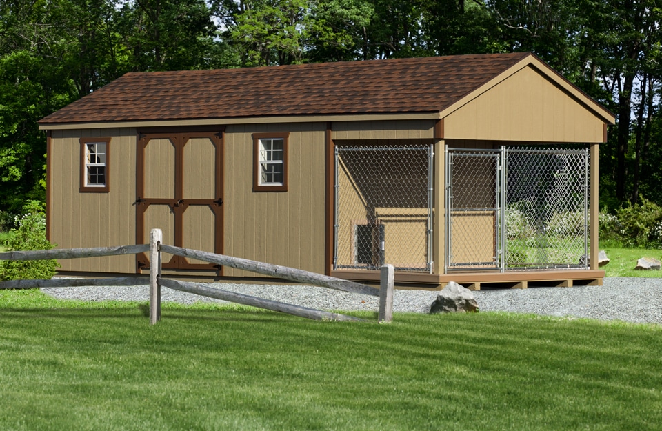tan and brown trimmed large outdoor dog kennel with brown shingle roof and an attached run