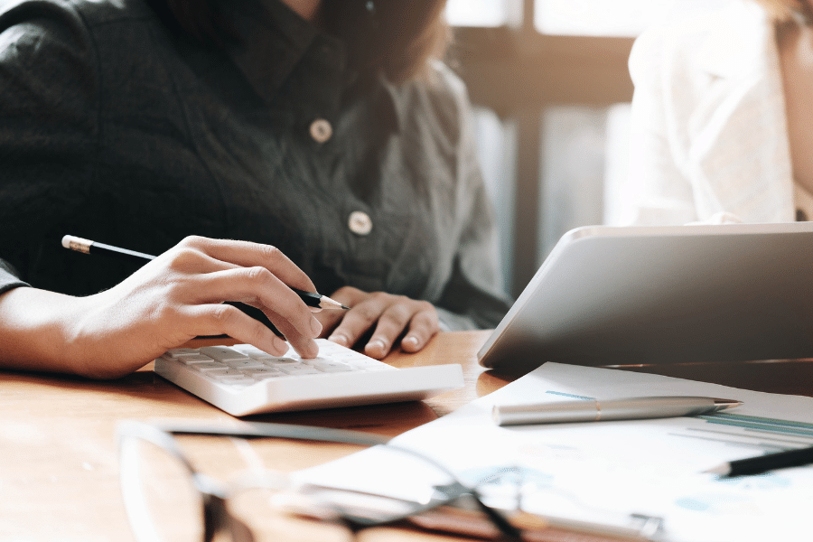 two people sitting at desk with papers and computers in front of them researching and planning for their dog kennel business