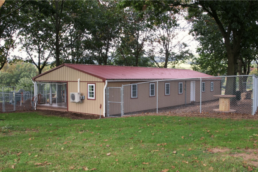 tan and red trimmed commercial dog boarding facility with outdoor playground area