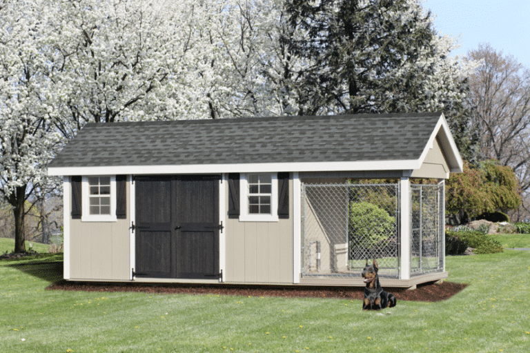 tan outdoor dog kennel with gray shingle roof with white trim black double doors and shutters and an attached run